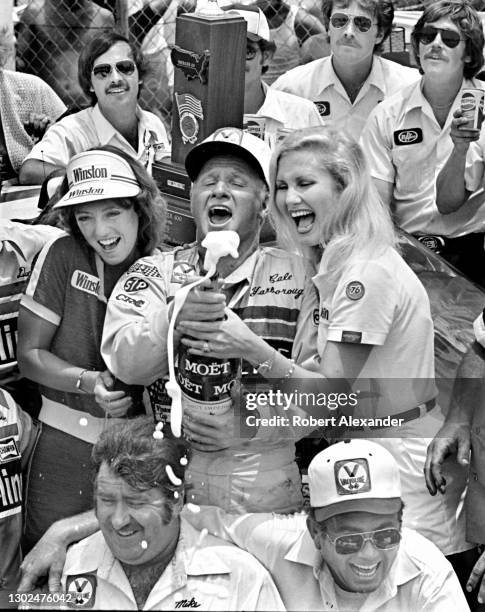 Driver Cale Yarborough pops the Moet champagne bottle in Victory Lane after winning the 1981 Firecracker 400 stock car race at Daytona International...