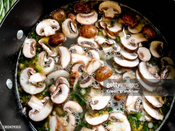 a simmering pot of shrimp pho soup with green onion, mushrooms, fresh garlic, bok choy, jalepeno, lemon slices and cilantro over pad thai noodles - cooked mushrooms stock pictures, royalty-free photos & images