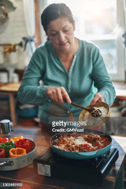 preparing stuffed bell peppers with ground meat in tomato sauce - rice stock pictures, royalty-free photos & images