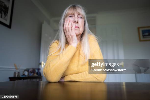 depressed senior woman sitting alone at home - domestic violence home stock pictures, royalty-free photos & images