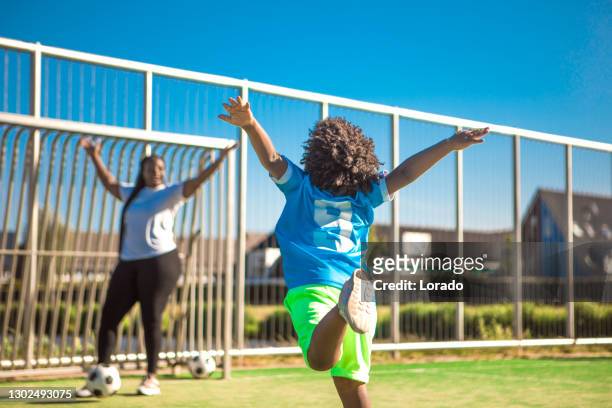 beautiful black family training on the football pitch - soccer mum stock pictures, royalty-free photos & images