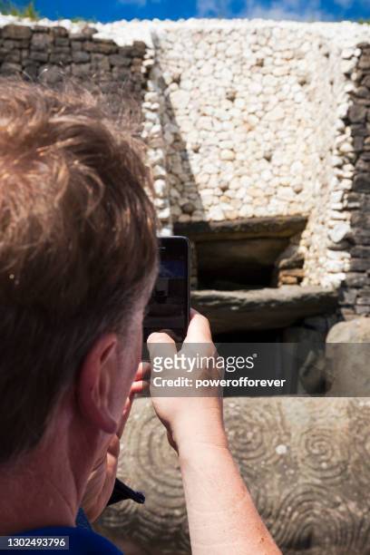 tourist taking photo at newgrange in county meath, irland. - bru na boinne stock-fotos und bilder