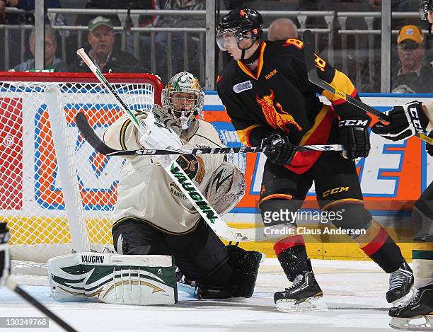 Michael Houser of the London Knights knocks a shot away from Adam Payerl of the Belleville Bulls in a game on October 21, 2011 at the John Labatt...
