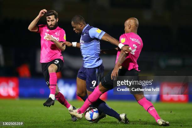 Uche Ikpeazu of Wycombe Wanderers is challenged by Andre Wisdom and Graeme Shinnie of Derby County during the Sky Bet Championship match between...