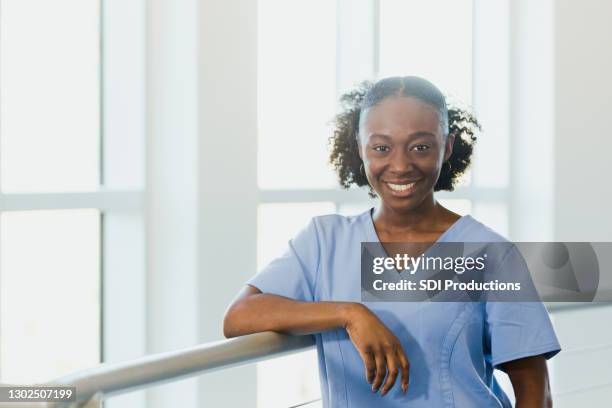 de jonge volwassen vrouwelijke verzorgingsstudent glimlacht voor camera - tandartsassistent stockfoto's en -beelden