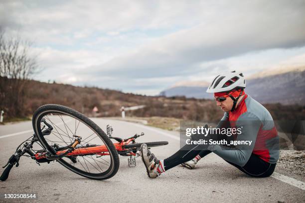 male cyclist fell of his bicycle on the road - crash imagens e fotografias de stock