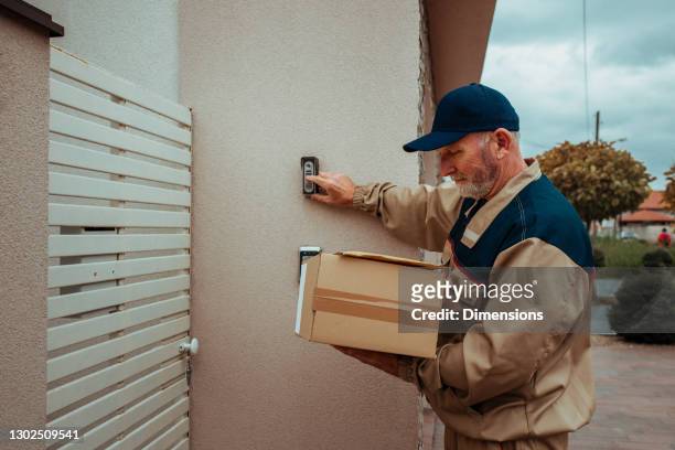 repartidor que lleva caja de cartón y suena en la campana de la puerta - door bell fotografías e imágenes de stock