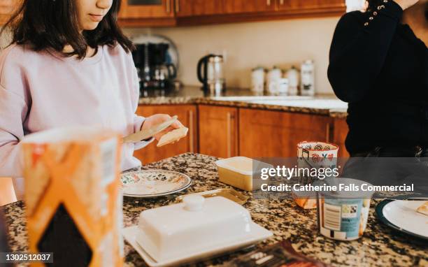 girl spreading butter on a cracker - margarine photos et images de collection