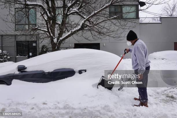 Orlando Flores, who recently moved to Chicago from Texas, digs out his wife's car after it was buried in snow on February 16, 2021 in Chicago,...