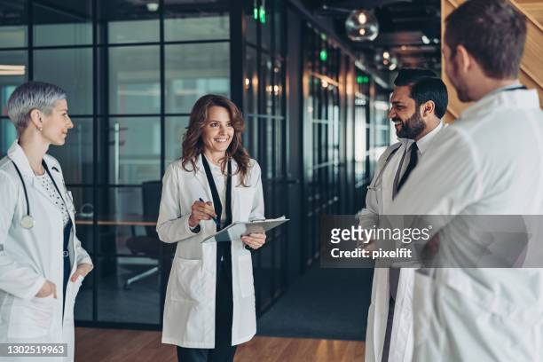 mature female doctor instructing colleagues - hospital leadership stock pictures, royalty-free photos & images