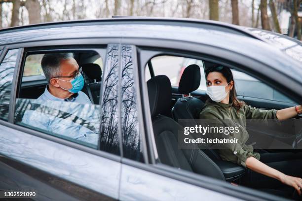 uomo anziano in sella al carshare con un autista donna durante la pandemia - passenger seat foto e immagini stock