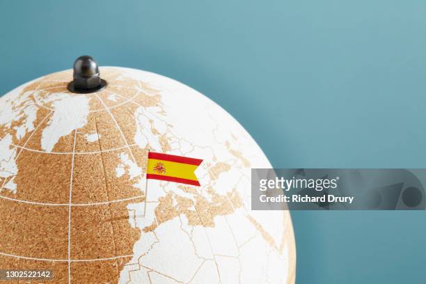 a world globe with a spanish flag pin showing spain - spanische flagge stock-fotos und bilder