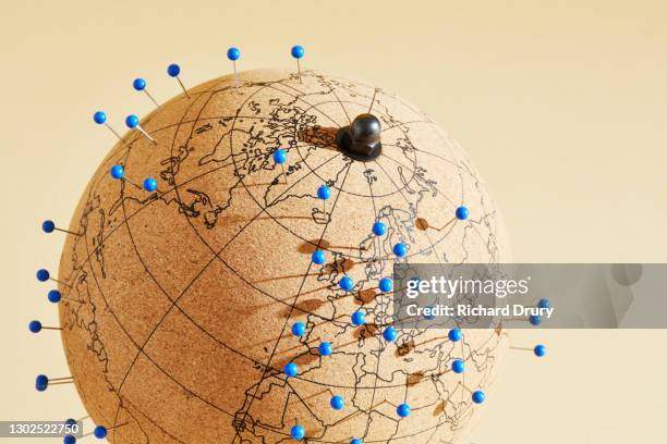 a world globe with many pins in different global locations - punaise stockfoto's en -beelden