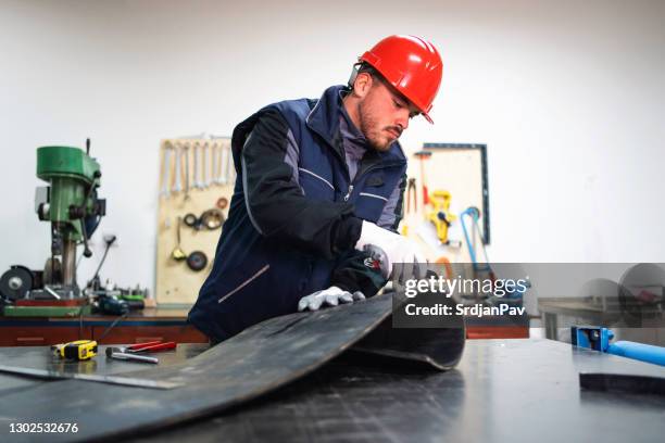 uomo, operaio, utilizzando un bisturi per tagliare la miscela nera di gomma in piccola produzione - lattice foto e immagini stock