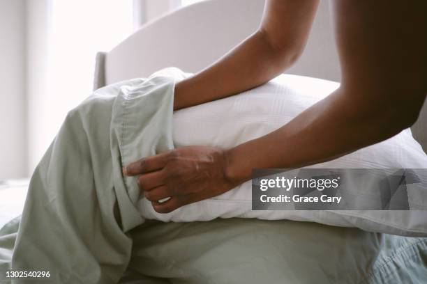 woman puts pillow into pillowcase - slopen stockfoto's en -beelden