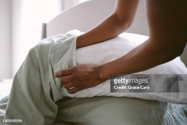 woman puts pillow into pillowcase - travesseiro imagens e fotografias de stock