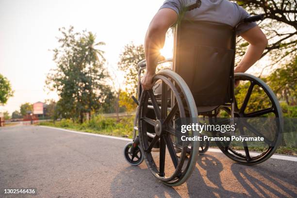 patient or disabled man is sitting in wheelchair in spring nature. - sedia a rotelle foto e immagini stock