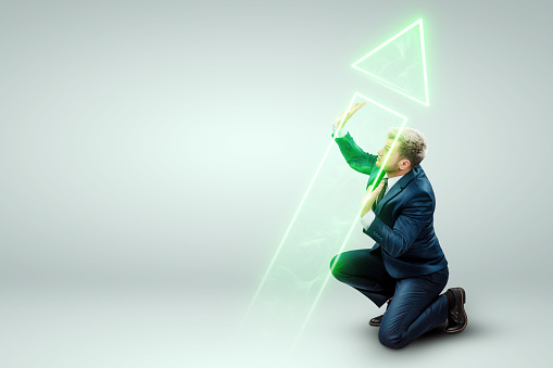 Бизнесмен в деловом костюме держится, поворачивает стрелку направления. Творческий фон. Концепция изменения маршрута.