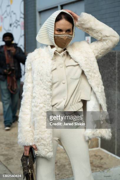 Woman wears Prada sunglasses, DVF cream jacket, Fendi bag with a matching Proenza Schouler shirt and pants outside of Spring Studios during New York...
