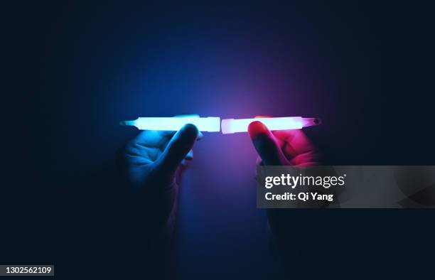 holding a glow stick in the dark - luce fluorescente foto e immagini stock
