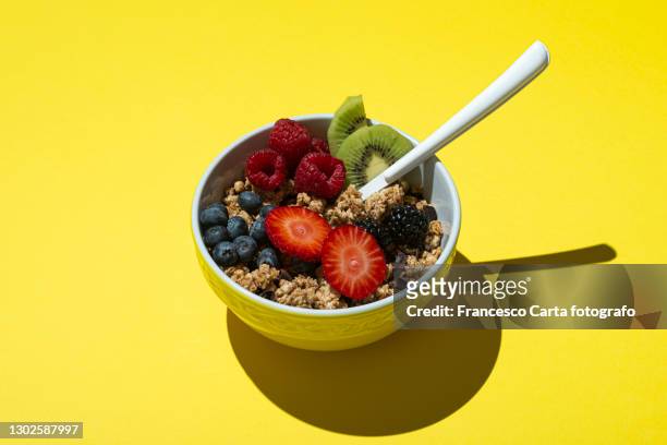 bowl with muesli ,chocolate and fruits on on yellow background - fibre food stockfoto's en -beelden