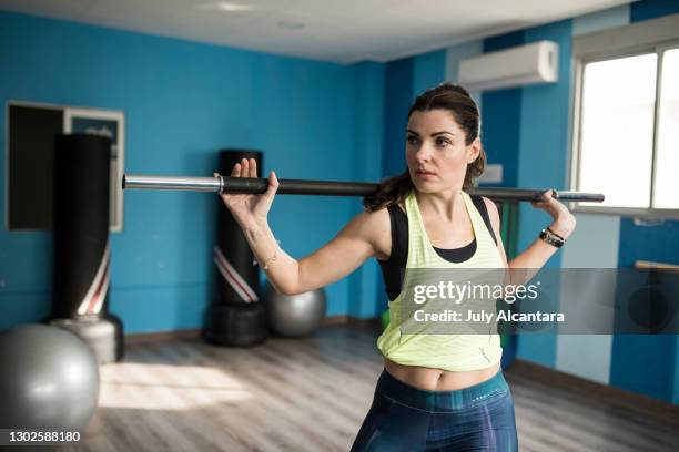 attractive 40 year old woman performs abdominal and barbell workout alone in a gym room - twisted stock pictures, royalty-free photos & images