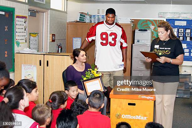 Cardinals Player Calais Campbel looks on as Office Max team member Kelli Roy reads a poem to winning teacher Andrea Gallegos during the Office Max "A...