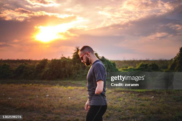 jeune homme avec différentes capacités finissant l’exercice à l’extérieur au crépuscule - amputé photos et images de collection