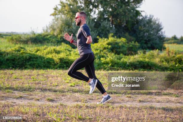 physically impaired young man jogging in nature - amputee running stock pictures, royalty-free photos & images
