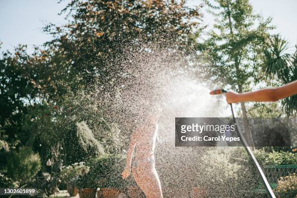 teenagers having fun  splashing water from hose in backyard - garden hose foto e immagini stock