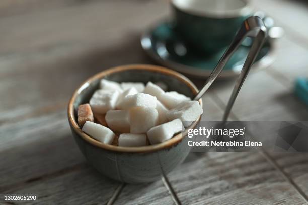 white lump sugar in a beautiful blue sugar bowl stands on a wooden table. junk food, unhealthy food. the sweet life - sugar cube stock pictures, royalty-free photos & images