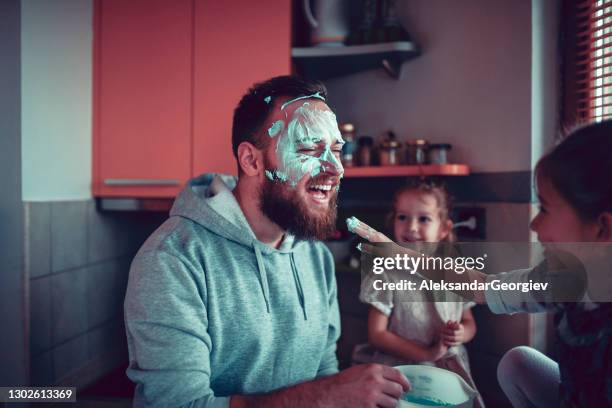 father getting face dirty with cake topping by female children - food fight stock pictures, royalty-free photos & images