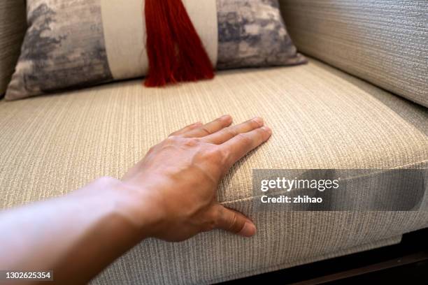 human hand touching the seat cushion of a cloth sofa - touching fabric stock pictures, royalty-free photos & images