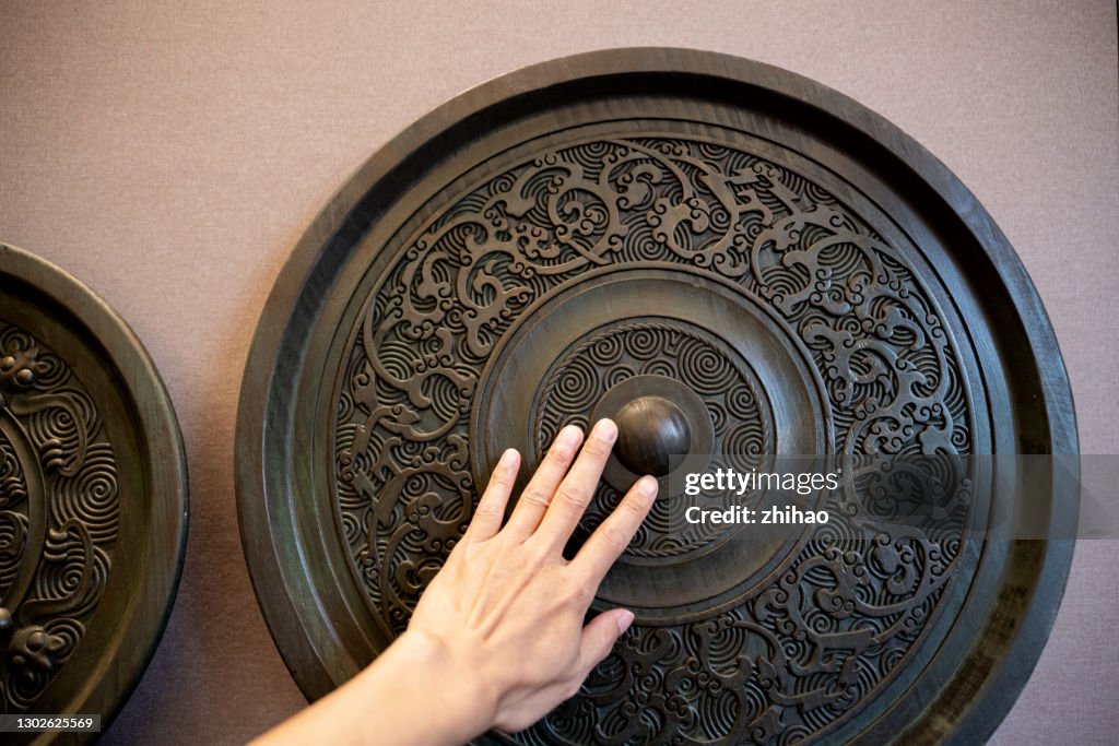 Human hand stroking ancient Chinese bronze mirror