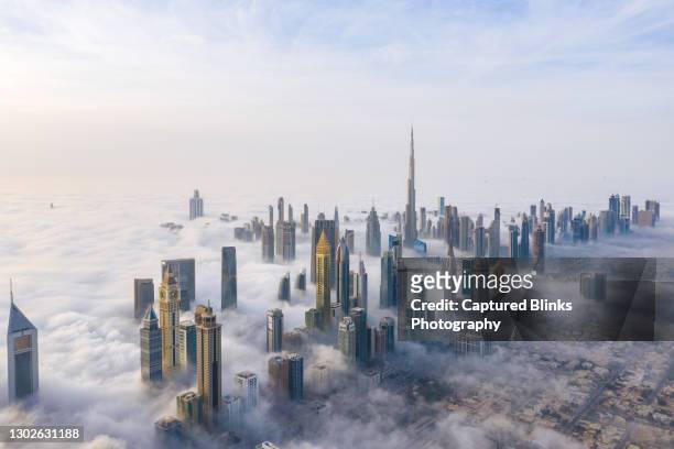 aerial view of dubai skyline covered in dense fog during winter season - dubai stock-fotos und bilder