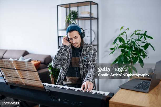 artista joven inspirado con hedphones tocando piano eléctrico en casa. - keyboard player fotografías e imágenes de stock
