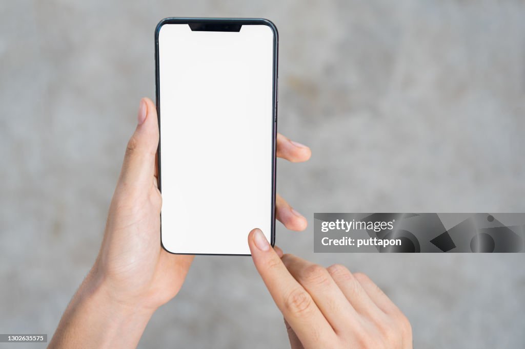 Close up of woman hand holding smartphone on white background, cropped hand using smartphone on the background of polished cement