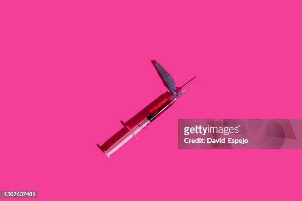 syringe over pink background - syringe full of blood stockfoto's en -beelden