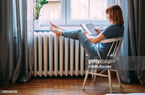 eine junge frau, die eine pause von der technik einnimmt - comfortable stock-fotos und bilder