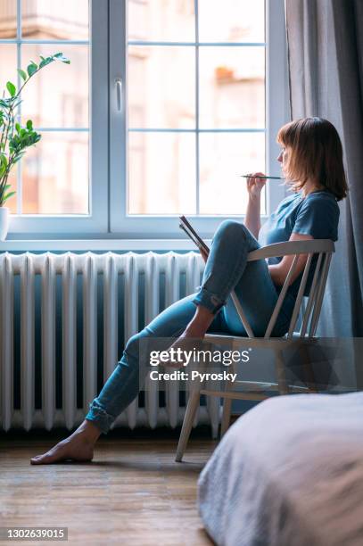 eine junge frau, die von zu hause aus studiert - daydreaming woman stock-fotos und bilder