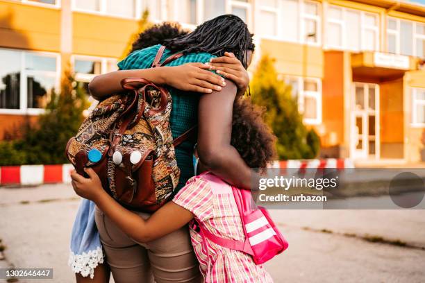 happy daughters embracing their mother after classes - back to school mom stock pictures, royalty-free photos & images