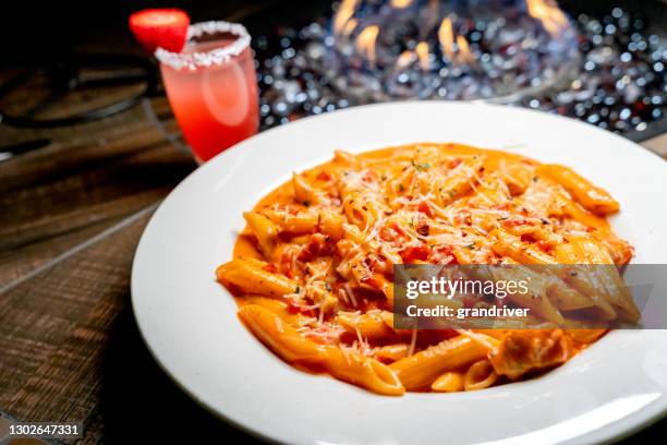 penne pasta alla vodka italian dinner with a cocktail in the background - penne pasta stock pictures, royalty-free photos & images