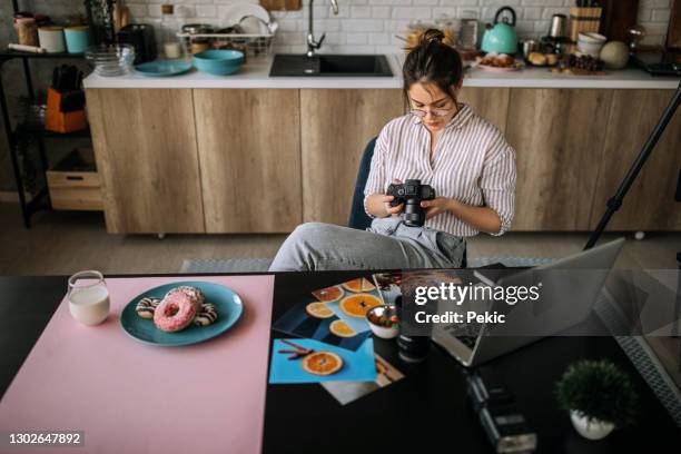 jonge vrouwelijke fotograaf die in haar studio van het huisbureau werkt - fotoredacteur stockfoto's en -beelden