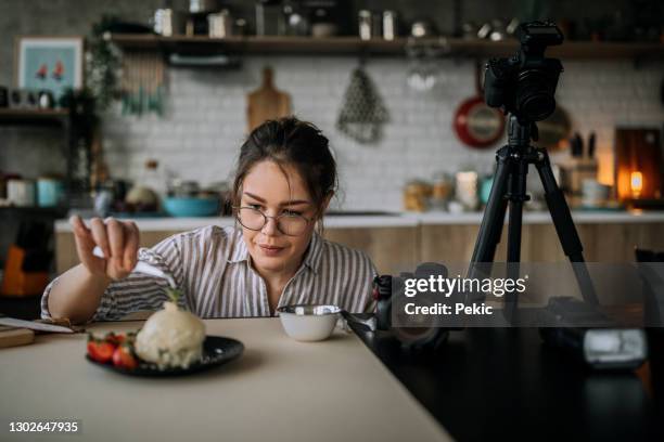 vrouwelijke voedselfotograpykunstenaar die haar cake klaar maakt voor het ontspruiten - one young woman only photos stockfoto's en -beelden