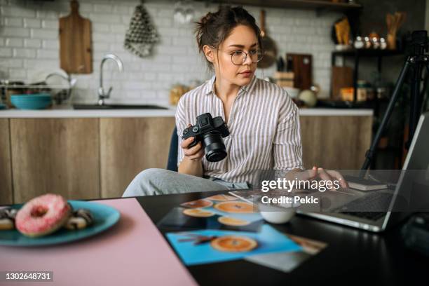 jonge vrouwelijke fotograaf die in haar studio van het huisbureau werkt - fotoredacteur stockfoto's en -beelden