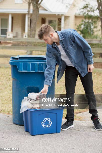junge kaukasische mann legt recycling-müll in mülleimer. - bordsteinkante stock-fotos und bilder