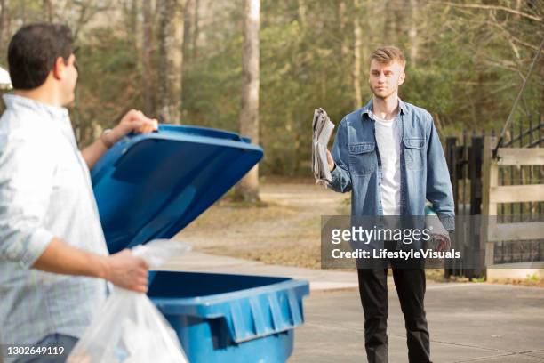 mid-adult latin descent and young caucasian men put recycle trash in bin. - carbon footprint reduction stock pictures, royalty-free photos & images