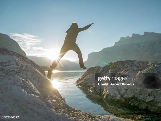 ung man hoppar över gapet över bergssjön - jumping sun bildbanksfoton och bilder