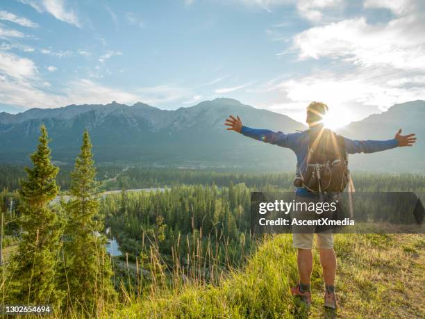 wanderer streckt arme aus auf bergbluff, sonnenaufgang - forest morning sunlight stock-fotos und bilder