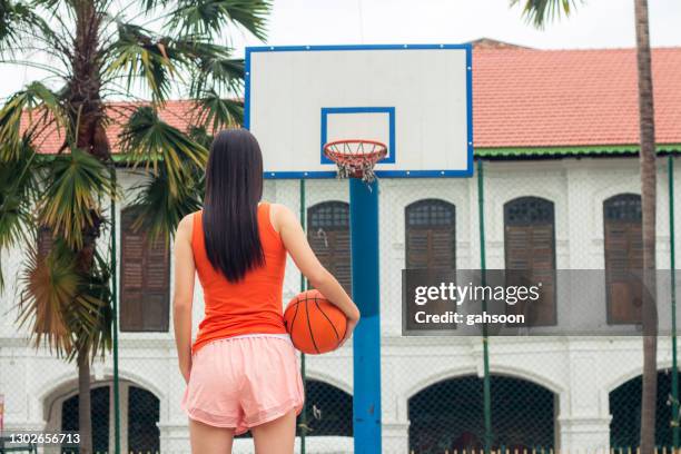 female basketball player holding basketball on street - basketball court stock pictures, royalty-free photos & images